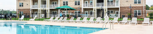 Exterior of Building with a Pool in Front and Multiple Loungers.