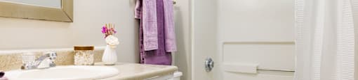 a bathroom with a white bathtub and a white sink with a purple towel