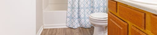 a bathroom with a white toilet next to a shower with a blue shower curtain