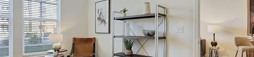 A bedroom with a bed, chair, and shelves.