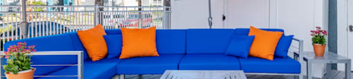 a patio with a blue couch and orange pillows and umbrellas