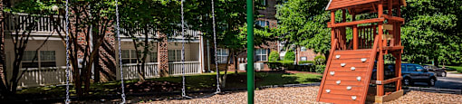 a playground with a swing set and a tree house