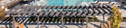 A large outdoor swimming pool surrounded by sun loungers and umbrellas at Boardwalk at Research Park apartments in Huntsville, AL.