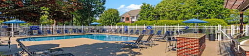 a swimming pool with blue lounge chairs and umbrellas