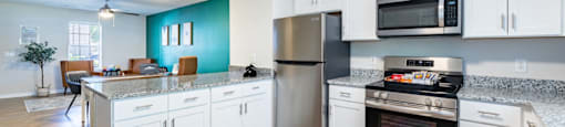 A kitchen with white cabinets and a stainless steel refrigerator.