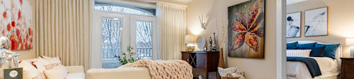 A living room with a white couch and a large painting on the wall.