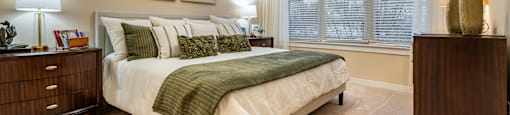 A bedroom with a bed, nightstand, and a painting on the wall.