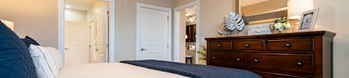 A bedroom with a large bed and a dresser with a mirror above it.