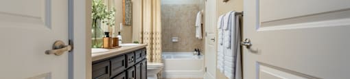 A bathroom with a white door and a beige floor.