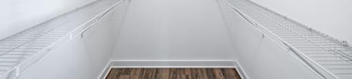 A white empty walk in fridge with a wooden floor.