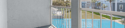 a balcony with a view of a pool and a building in the background
