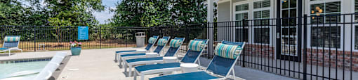 a pool with lounge chairs next to a house