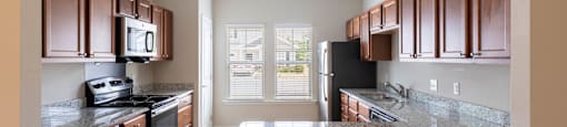 an empty kitchen with granite counter tops and wooden cabinets