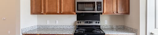 a kitchen with wood cabinets and black appliances and granite counter tops