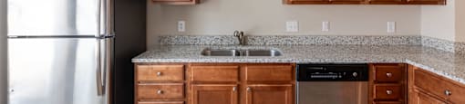 an empty kitchen with wooden cabinets and a stainless steel refrigerator
