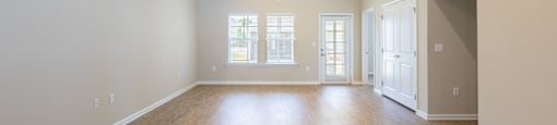 an empty living room with a hard wood floor and white walls
