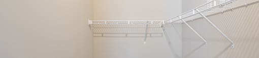 an empty walk in closet with white shelves and a white wall with a wire rack