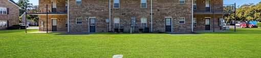 A large building with a flat roof and a green lawn in front.