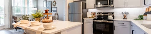 A modern kitchen with white cabinets and stainless steel appliances.