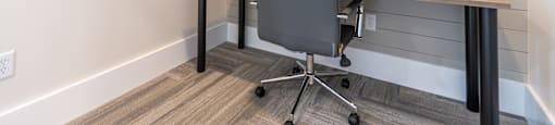 A grey office chair sits in front of a wooden desk.