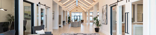 A long hallway with a rug in the middle and chairs on the left at SW 38th Avenue Apartments in Ocala, FL.
