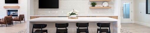 A modern kitchen with a white brick wall and a long white island.