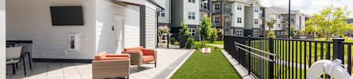 A patio with a white couch and a black fence.