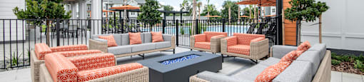 A patio with two chairs and a table with orange cushions.
