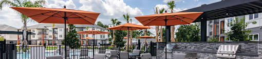 A patio with tables and chairs under orange umbrellas.