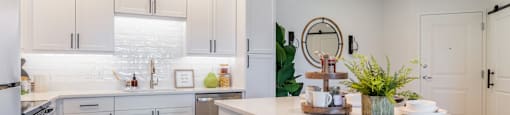 A modern kitchen with white cabinets and a wooden floor.