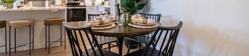 A modern dining room with a round mirror and a dining table with chairs.