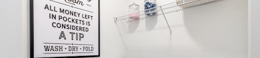 A laundry room with a sign that says "The Laundry Room - All money left in pockets is considered a tip".