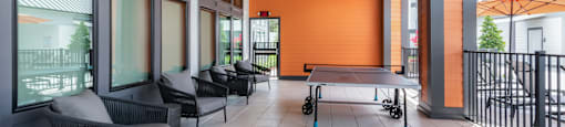 A patio with a table and chairs and a ping pong table.