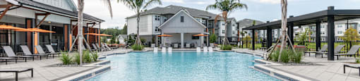 A large swimming pool surrounded by palm trees and lounge chairs at SW 38th Avenue Apartments in Ocala, FL