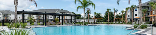 A swimming pool surrounded by palm trees and a building in the background.