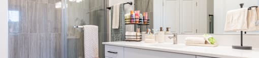 A bathroom with a white counter and a glass shower.
