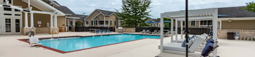A pool with a blue umbrella and lounge chairs.