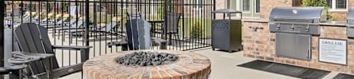 A patio area with a fire pit and chairs.
