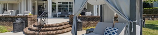 a patio with a couch and umbrellas in front of a house