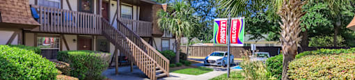 a sidewalk in front of a building with palm trees