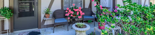 the front porch of a house with chairs and potted plants