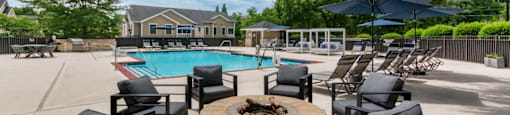 A poolside area with black chairs and a fire pit.