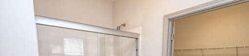 A white bathroom with a walk in shower and a white door at 2918 North Winstead Commons apartments in Greensboro, NC.