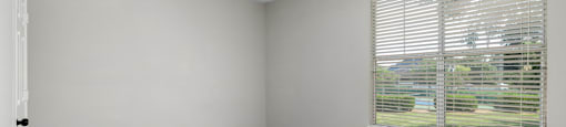 an empty bedroom with a large window and carpeting