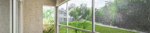 a screened in porch with a view of a grassy area and a building in the background