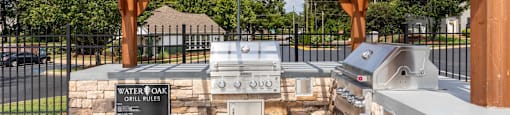 A water booth with grills and a sign that says "Grill Rules" is under a wooden pergola.