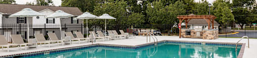 A large swimming pool with a red brick border and a white fence surrounding it.