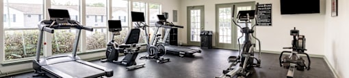 a gym with cardio equipment and windows in a building