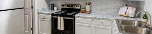 a kitchen with white cabinets and black appliances and a stainless steel refrigerator