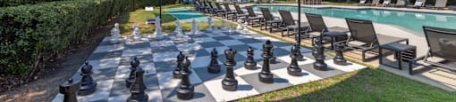 a large chess board is set up next to a swimming pool